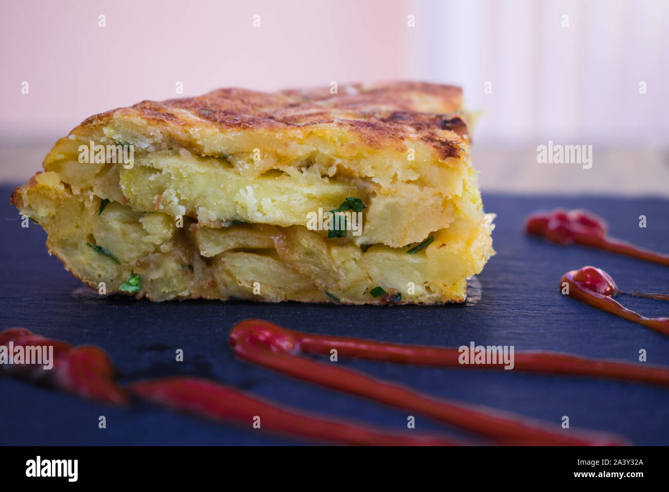 Frittata spagnola con ketchup, sulla superficie nera Foto Stock