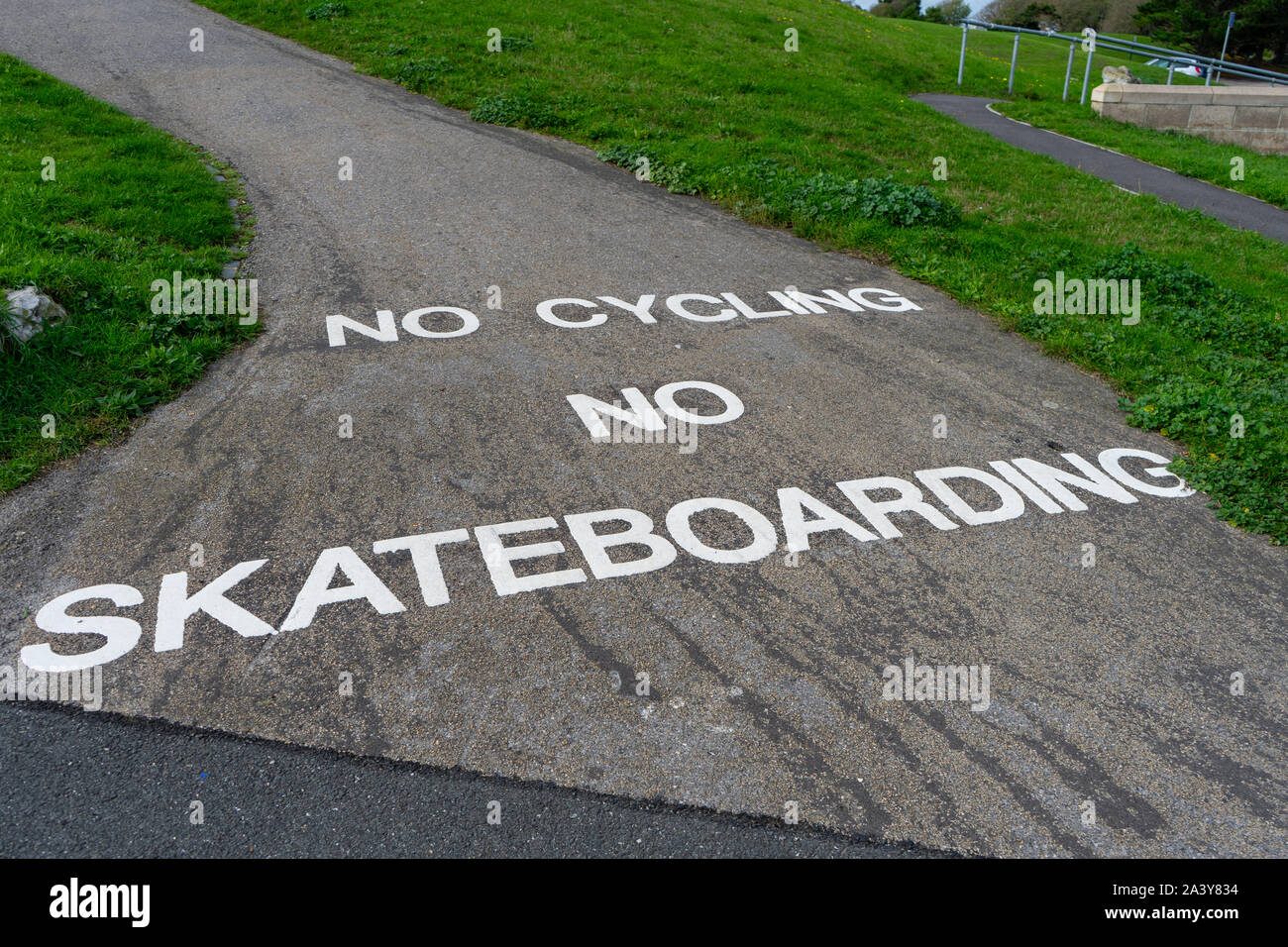 Un segno dipinto sul terreno con il messaggio Nessun escursioni in bicicletta e non lo skateboard Foto Stock
