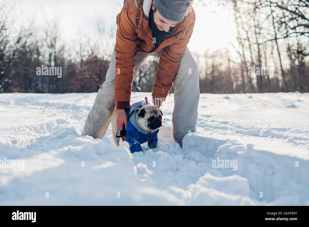 Pug dog passeggiate sulla neve con il suo proprietario. L'uomo gioca con pet all'aperto Foto Stock