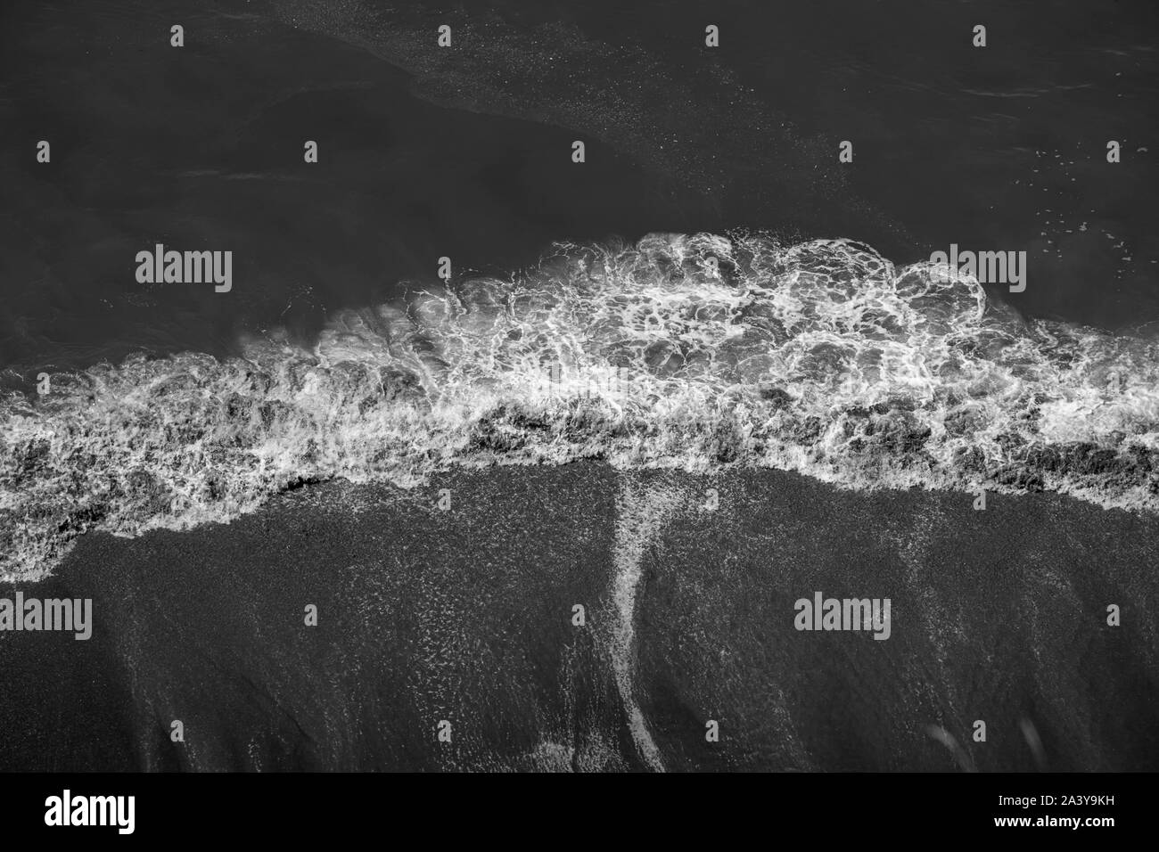 Guardando le onde che si infrangono sulla spiaggia in bianco e nero Foto Stock