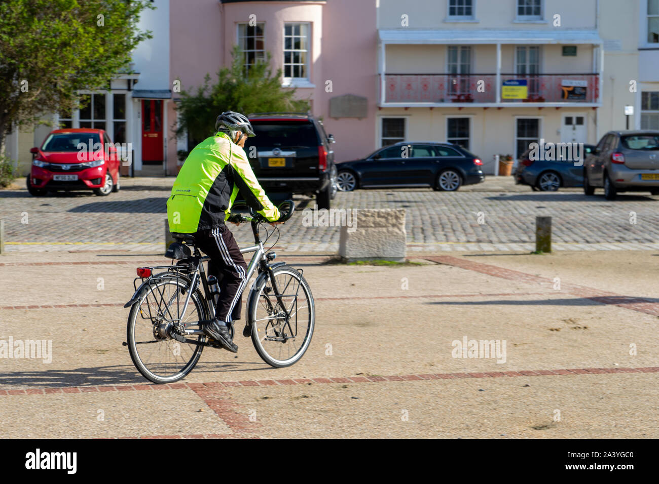 Un uomo di mezza età in bicicletta indossare indumenti ad elevata visibilità e un ciclo casco Foto Stock