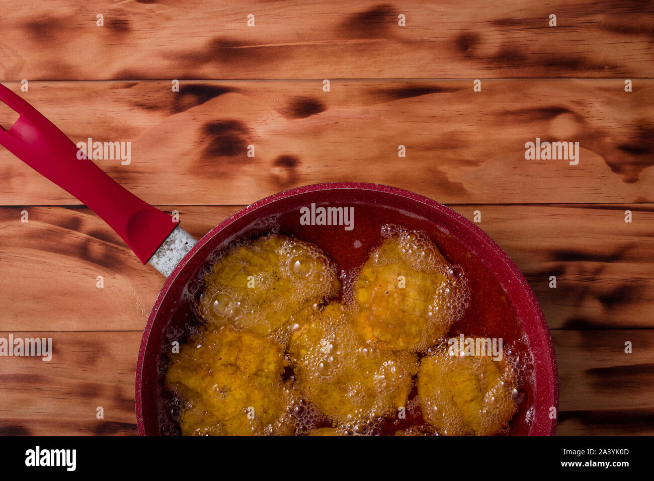 Fritte frittelle di banane in un rosso padella Foto Stock