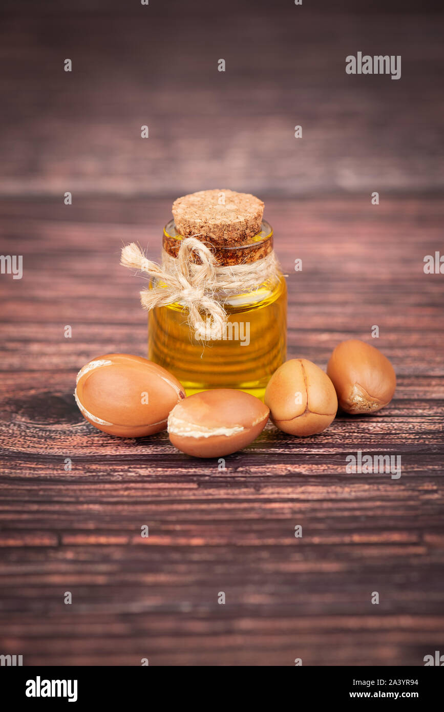 Olio di Argan, su sfondo di legno. I dadi di Argan e semi, per prodotti cosmetici e prodotti di bellezza. Naturali frutto di argan dal Marocco. Foto Stock