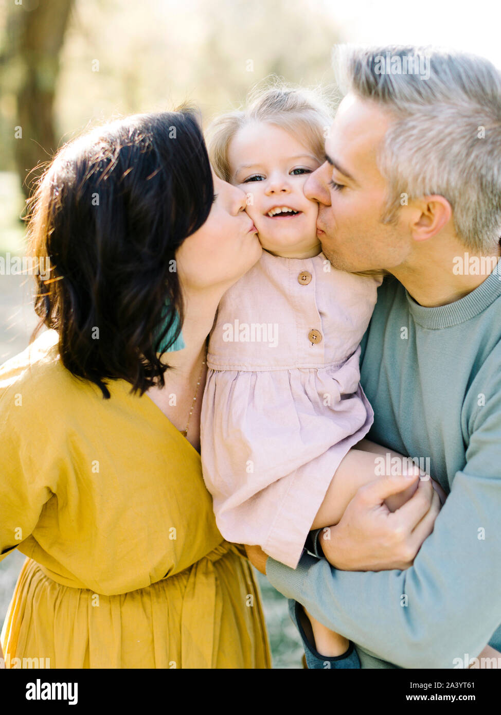 I genitori di baciare la loro figlia di guance Foto Stock