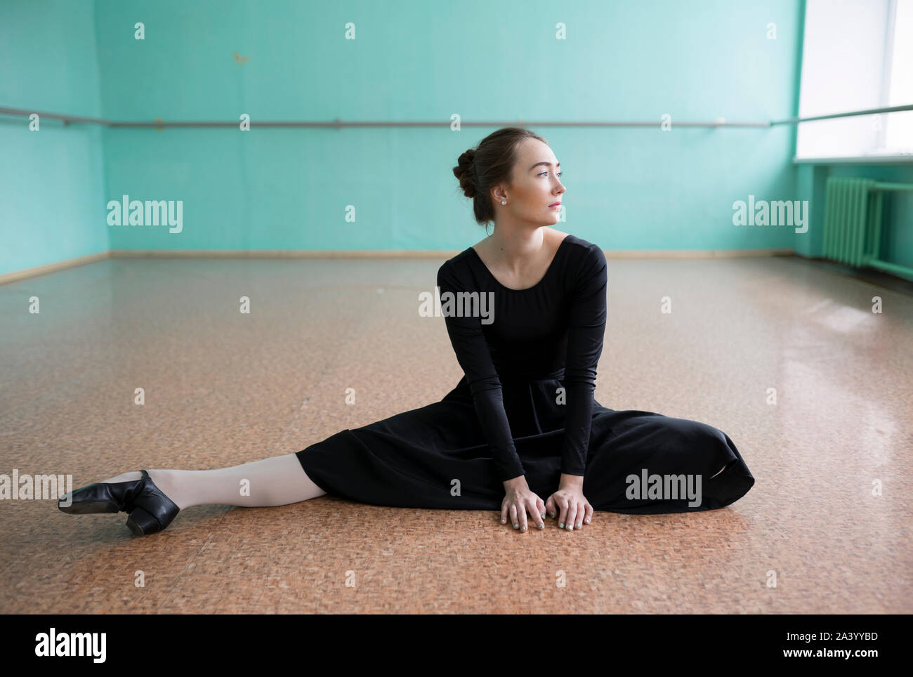 Ballerina indossando abito nero lo stiramento in studio Foto Stock