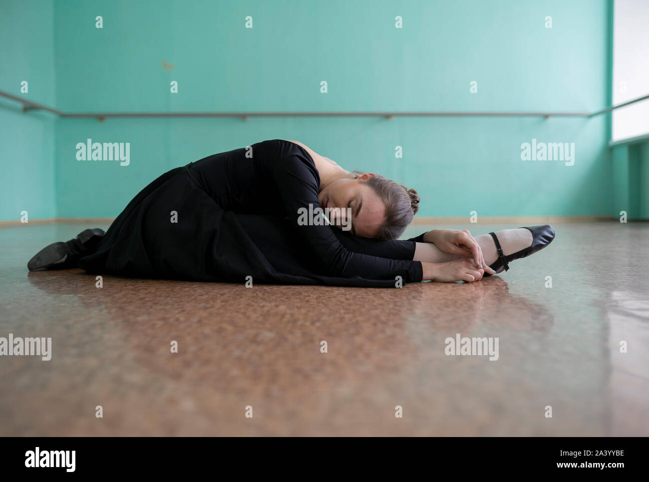 Ballerina indossando abito nero lo stiramento in studio Foto Stock