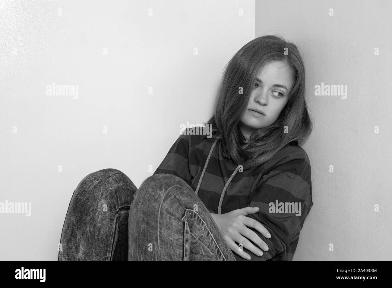 Giovane ragazza caucasica donna seduta sul pavimento, piangere, sconvolto, abusato o premuto. In bianco e nero Foto Stock