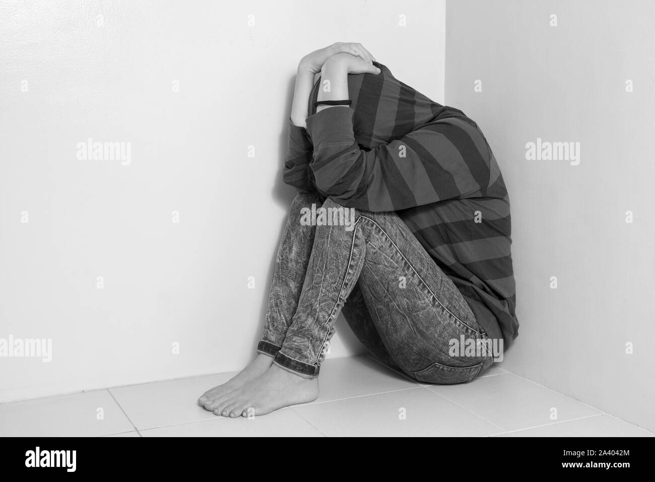 Giovane ragazza caucasica donna seduta sul pavimento, piangere, sconvolto, abusato o premuto. In bianco e nero Foto Stock