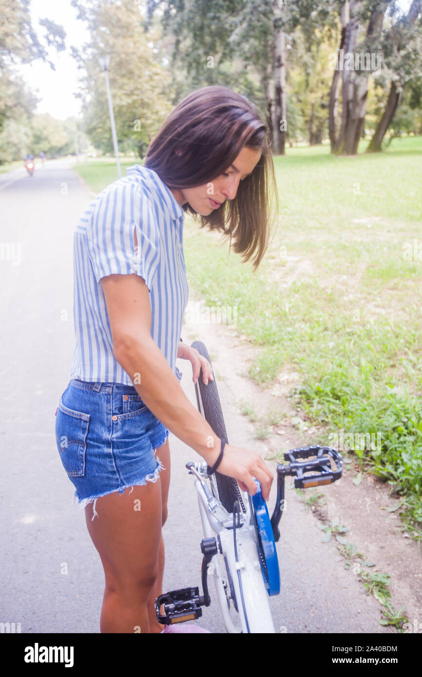 Giovane sportivo da donna con la bicicletta, indossano jeans pantaloni corti, godere di un giorno di estate in natura. Foto Stock