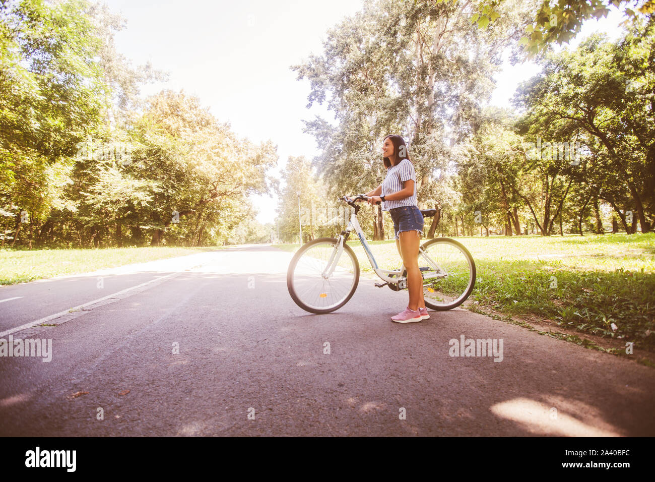 Giovane sportivo da donna con la bicicletta, indossano jeans pantaloni corti,  godere di un giorno di estate in natura Foto stock - Alamy