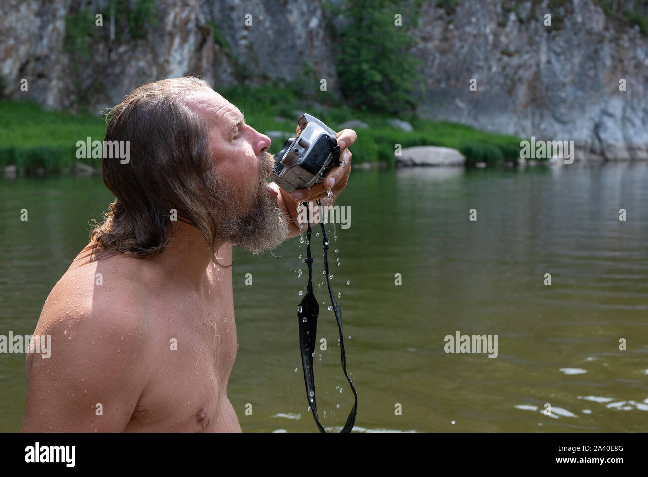 Un uomo controlla la resistenza all'acqua della telecamera in un fiume. outdoor Foto Stock