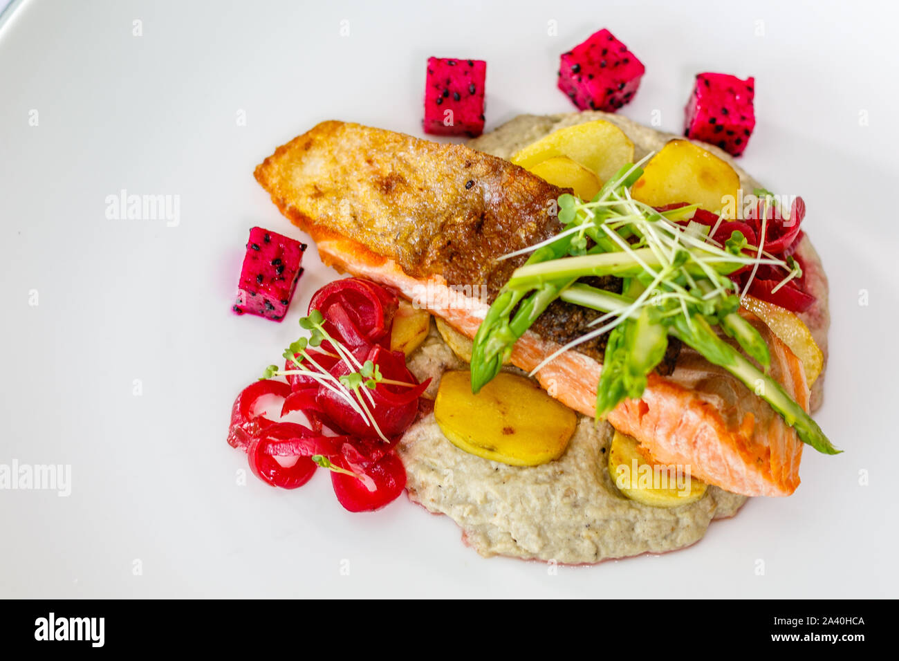 Croccante scuoiati atlantico Salmone con patate arrosto, Carne saltata asparagi e baba ghanoush, decorate con i germogli di soia e frutta drago. Vista superiore Foto Stock