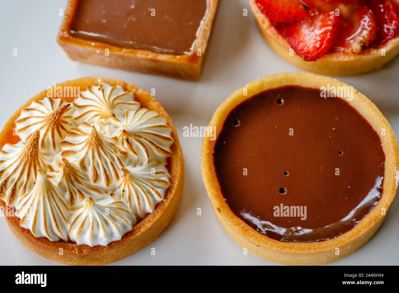 Mini limone crostata di meringa e cioccolato fondente tart. Crostata di fragole e salate crostata di caramello sul retro. Vista dall'alto. Foto Stock