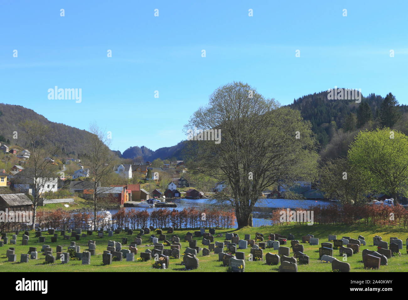 Vista sopra il cimitero e il villaggio al fiordo in Mjøsvågen, Hosanger, su Osterøy in Norvegia durante la tarda estate. Foto Stock