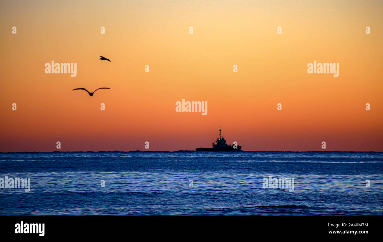 Barche da pesca sotto un cielo arancione Foto Stock