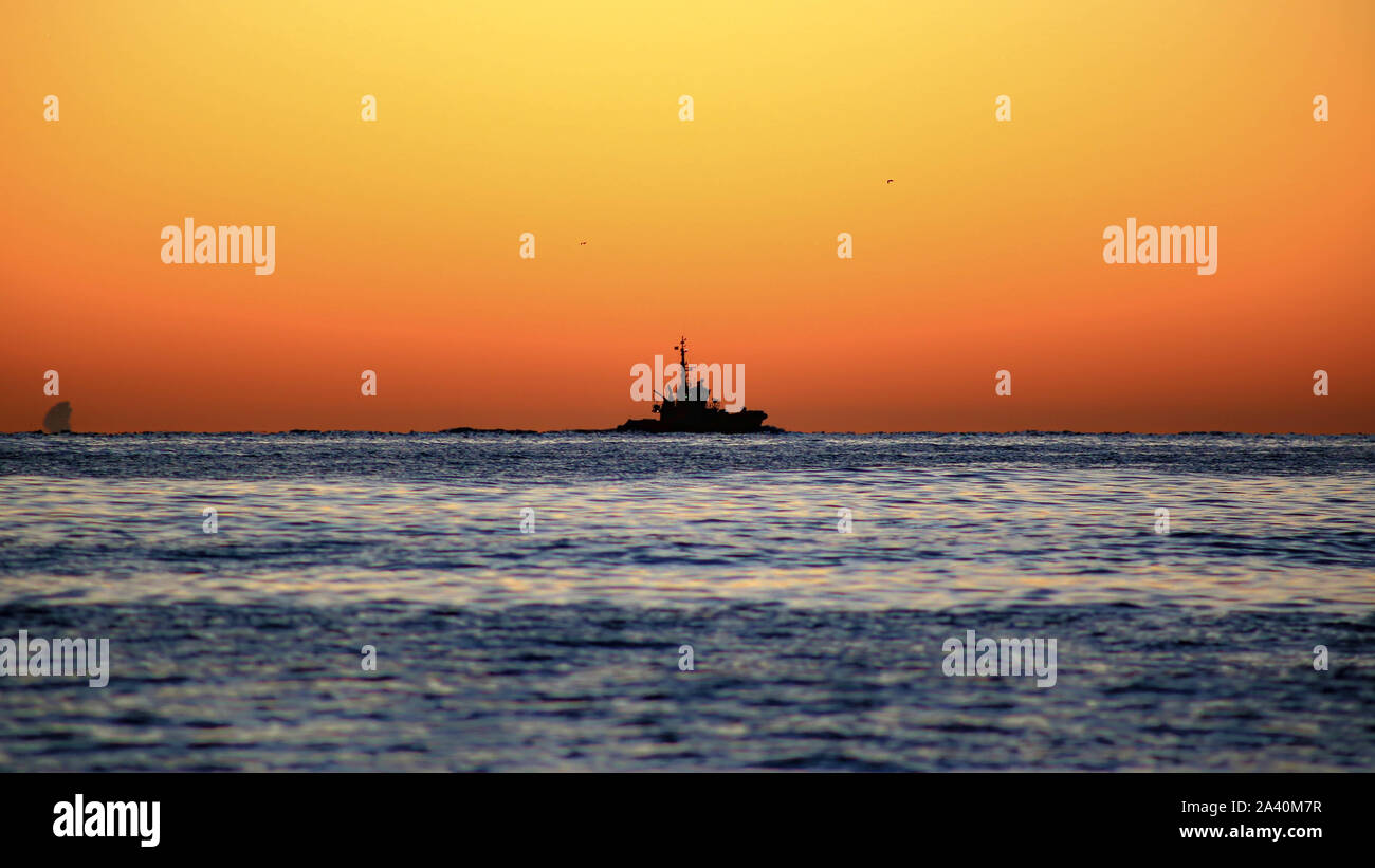 Barche da pesca sotto un cielo arancione Foto Stock