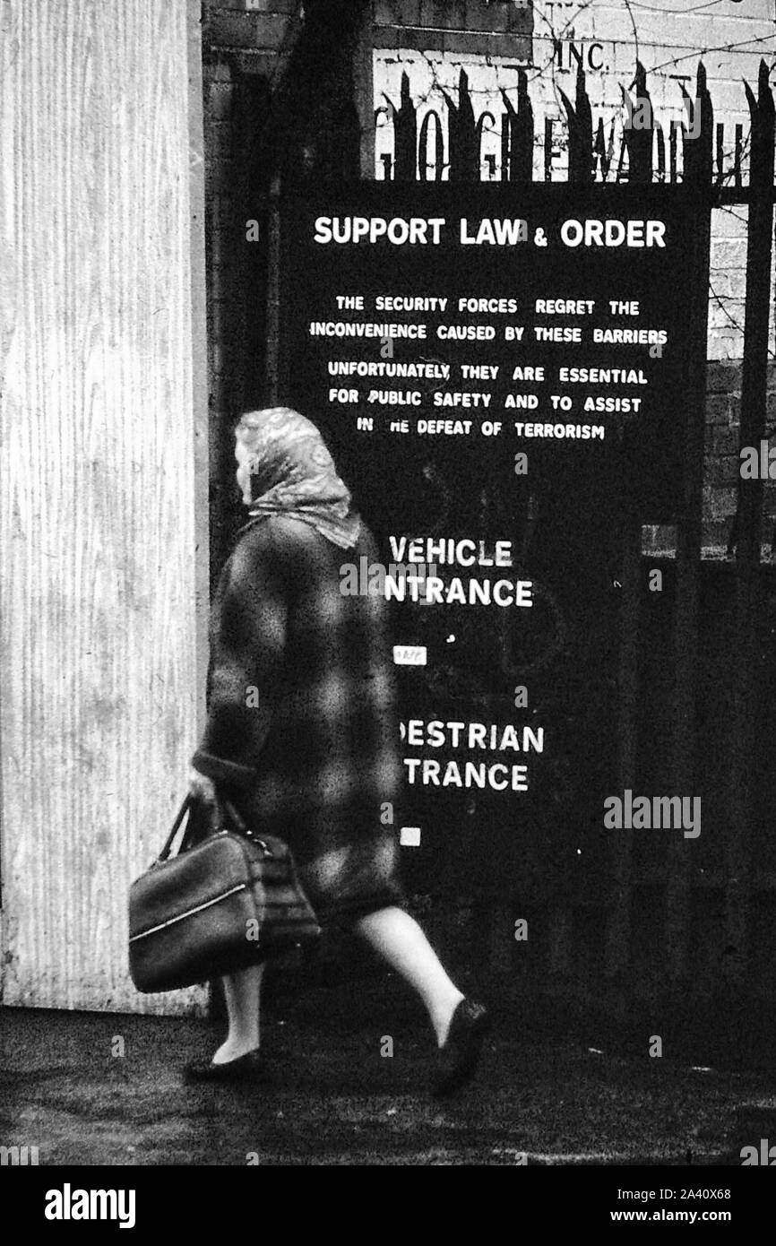 Una donna che porta un sacco a piedi passato un segno 'Supporto legge & ordine' a Belfast nel 1972, l'Irlanda del Nord, Regno Unito Foto Stock