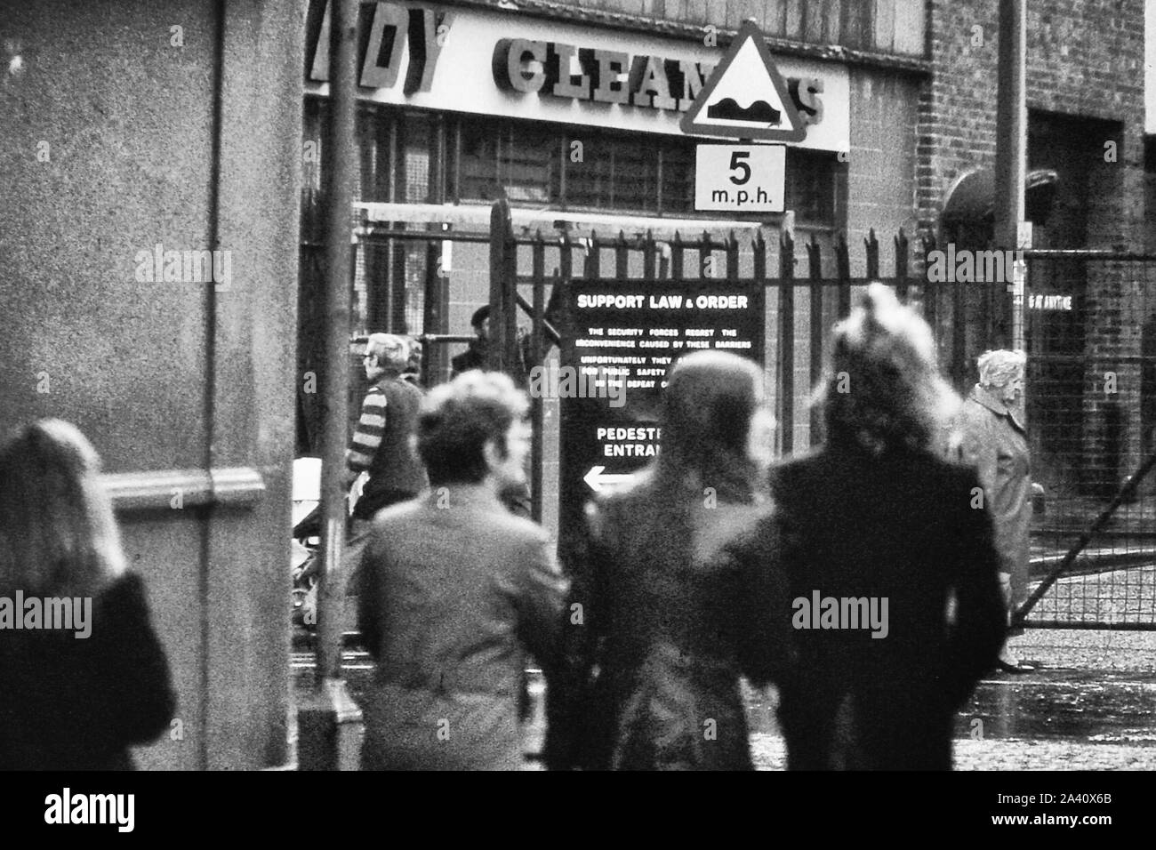 Le donne a camminare lungo una recinzione e un segno 'Supporto legge & ordine' a Belfast nel 1973, l'Irlanda del Nord, Regno Unito Foto Stock