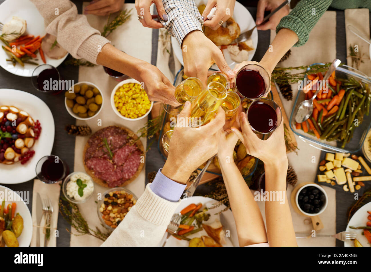 Angolo di alta vista di persone la tostatura con bicchieri di champagne e vino a tavola mentre si celebra la Giornata del Ringraziamento Foto Stock