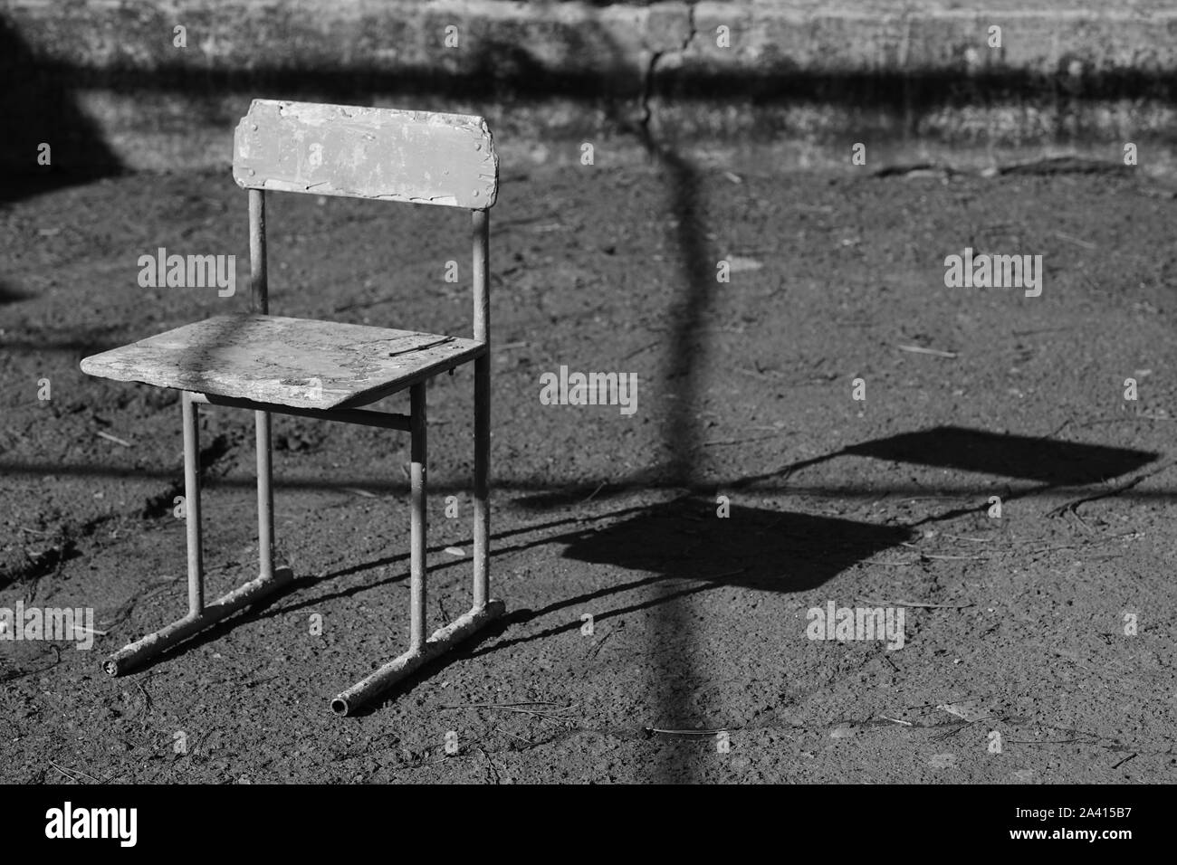 Vecchia sedia in cortile rurale. Asfalto pavimento in pietra. Disco di luce e ombra. BW. Foto Stock