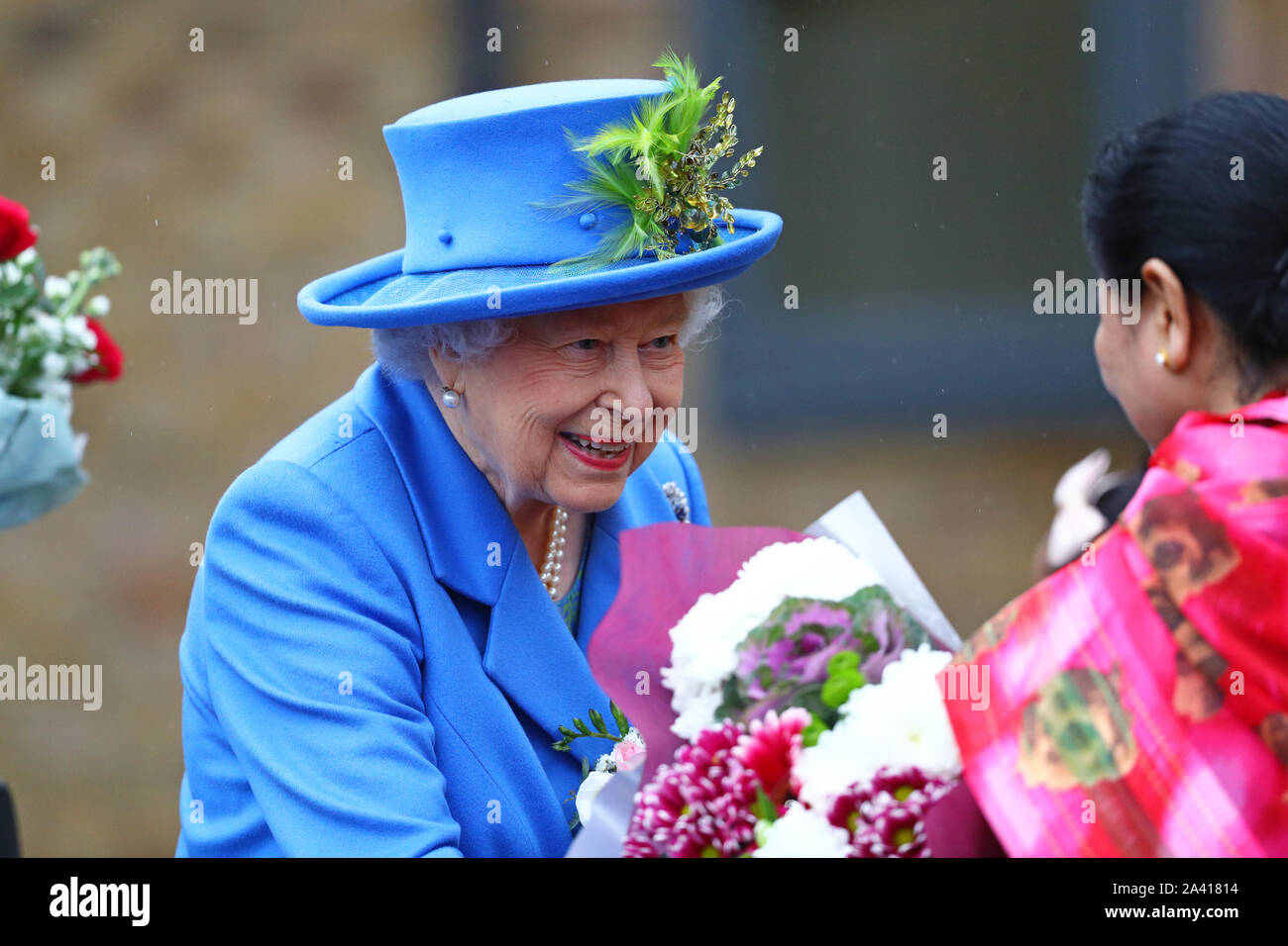Queen Elizabeth II riceve un mazzo di fiori da un membro del pubblico come lei arriva a visitare Haig alloggiamento fiducia, Morden, Londra, dove lei si aprirà ufficialmente il loro nuovo sviluppo di alloggiamento per le forze armate di veterani e l'ex-community del servizio. Foto Stock