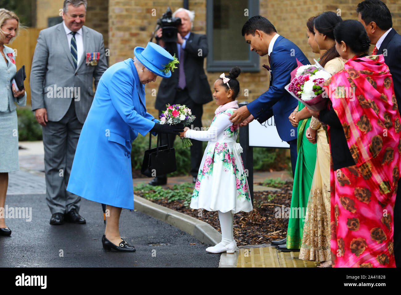 Queen Elizabeth II riceve un mazzo di fiori da un membro del pubblico come lei arriva a visitare Haig alloggiamento fiducia, Morden, Londra, dove lei si aprirà ufficialmente il loro nuovo sviluppo di alloggiamento per le forze armate di veterani e l'ex-community del servizio. Foto Stock