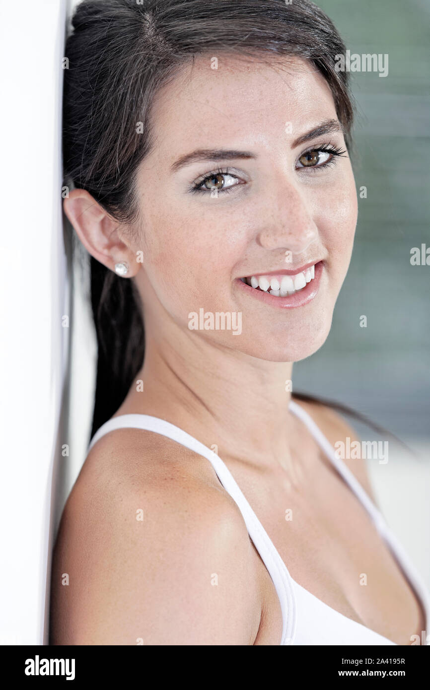 Bella giovane donna appoggiata contro il muro bianco riposo dopo esercizio Foto Stock