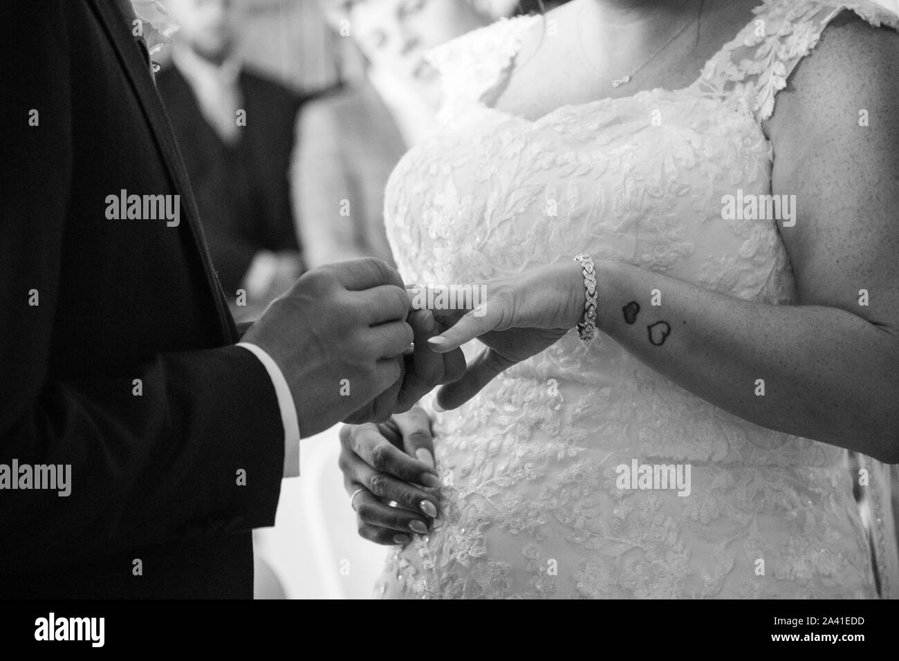 Sposa e lo sposo in prossimità delle loro mani come si scambiano gli anelli sul loro giorno delle nozze, facce non sono visibili in questa immagine, il giorno del matrimonio lo scambio degli anelli Foto Stock