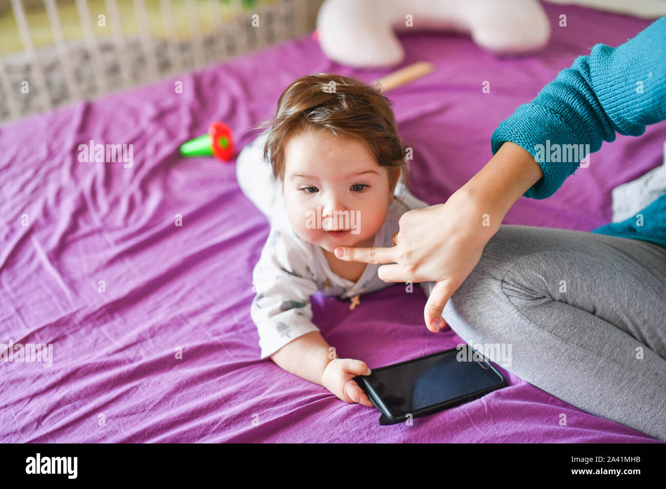 Piccolo bambino con un telefono. sul letto. conoscenza dei dispositivi mobili. Piccolo bambino con il telefono cellulare. Little baby in casuale coloratissimi capi di abbigliamento a righe con Foto Stock