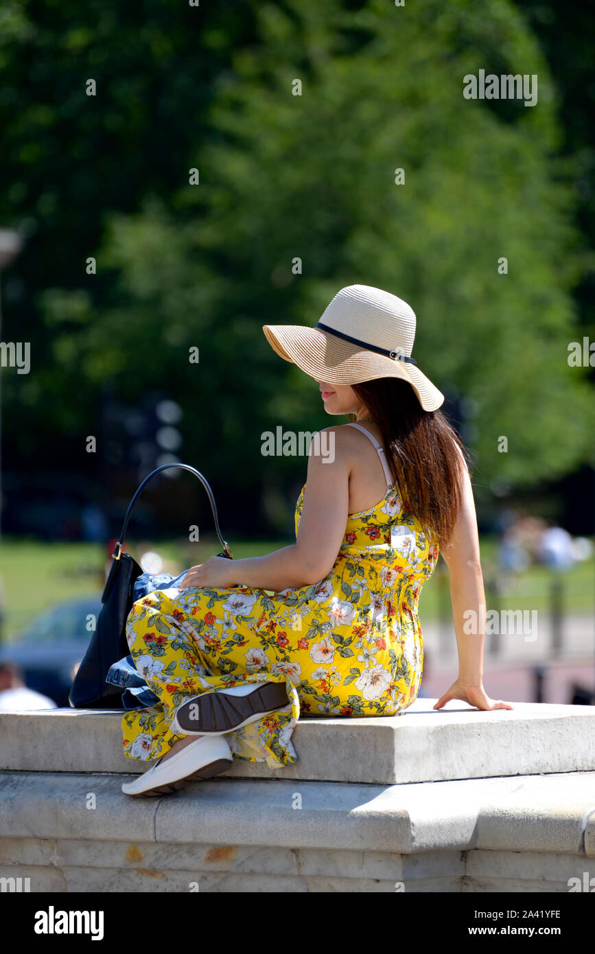 Londra, Inghilterra, Regno Unito. Giovane donna che posano per una foto dal Victoria Memorial in abiti estivi e hat Foto Stock