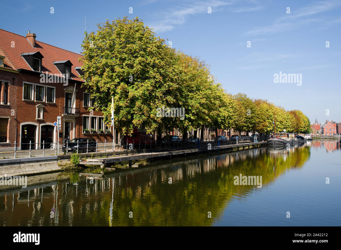 Alberi appena iniziando a girare a colori autunnali nel mese di settembre si riflettono nel canale in Bruges, Belgio. Foto Stock