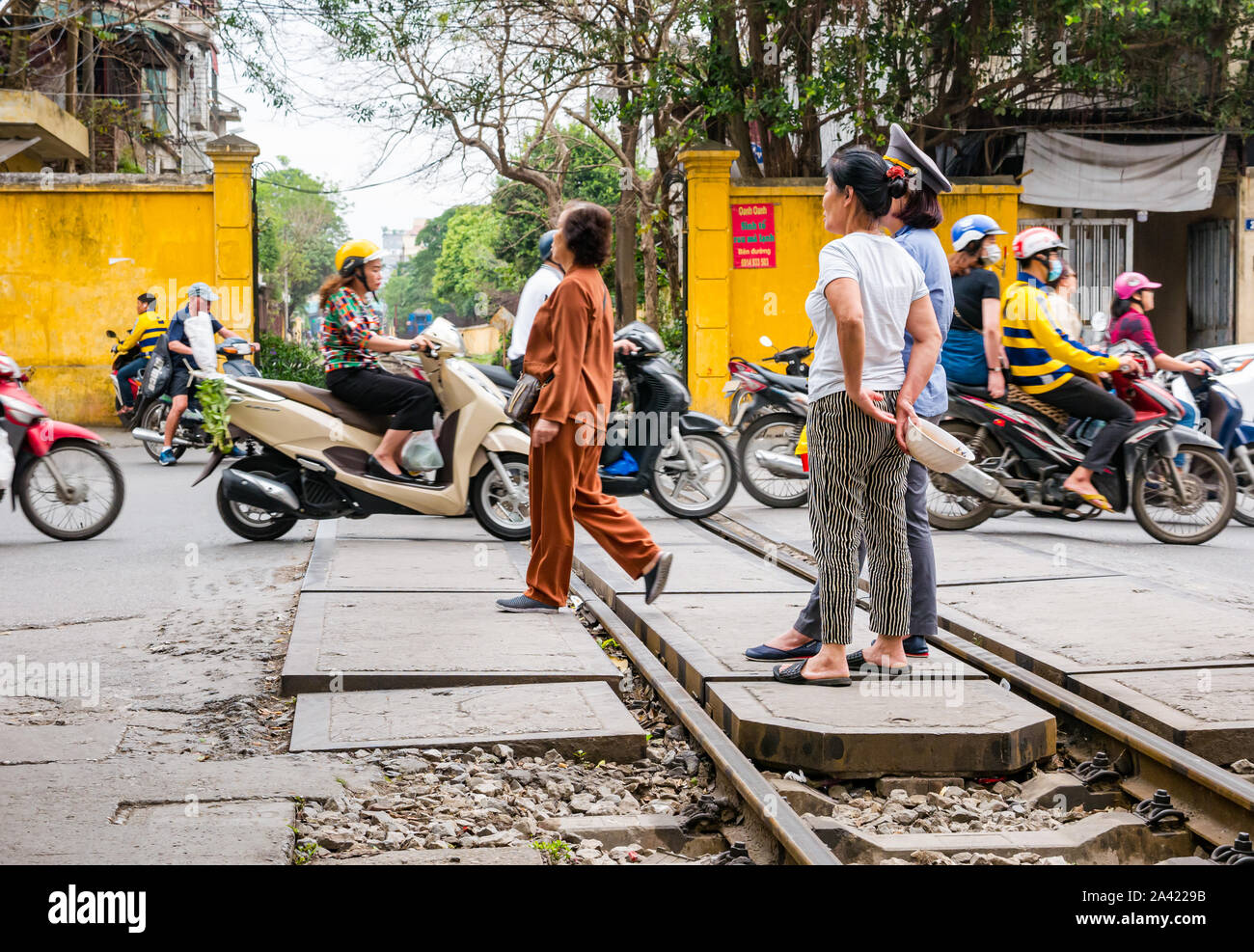 Protezione del treno con scooter e il traffico che attraversa la linea ferroviaria, villaggio ferroviario o treno Street, Hanoi, Vietnam Asia Foto Stock