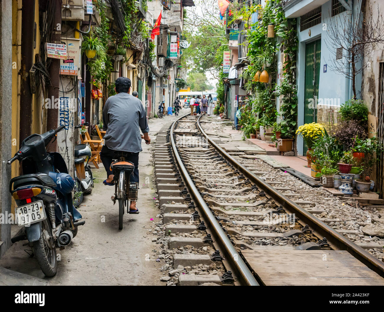 Uomo in bicicletta nel Villaggio Ferroviario corsia stretta con linea ferroviaria vicino a vecchie case, Hanoi, Vietnam Asia Foto Stock