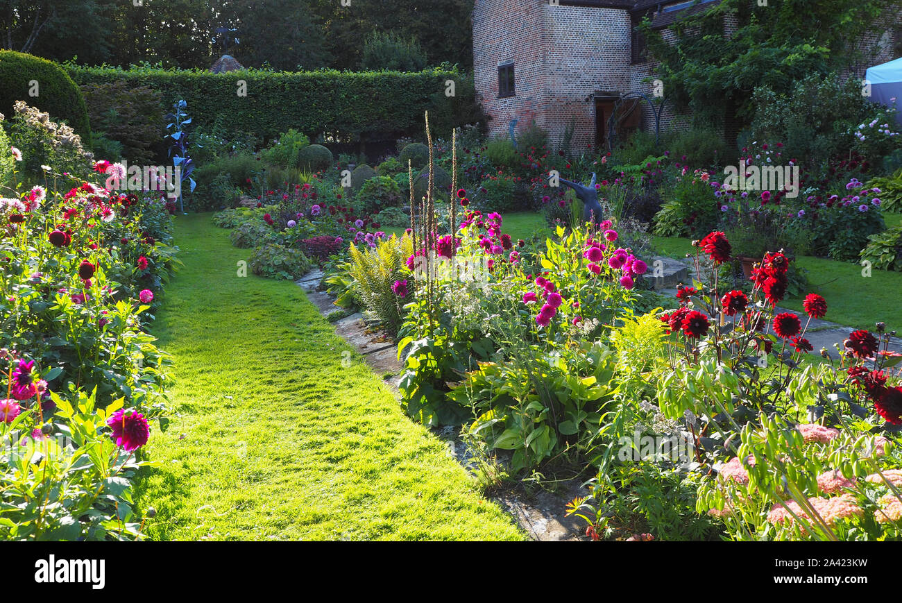 Il Sunken garden a Chenies, Buckinghamshire su una soleggiata sera nel settembre;il restaurato Pavilion.Colorata varietà dahlia e luminoso percorso erboso. Foto Stock