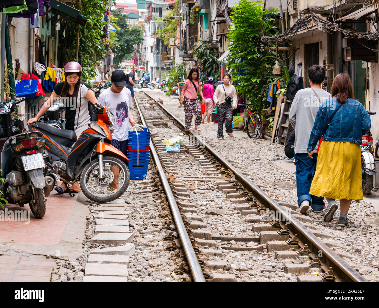 La popolazione locale e scooter in Villaggio Ferroviario corsia stretta con linea ferroviaria, Hanoi, Vietnam Asia Foto Stock