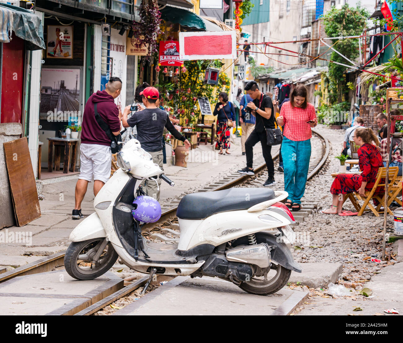 I turisti in caffè nel villaggio ferroviario o treno Street, strette corsie con linea ferroviaria, Hanoi, Vietnam Asia Foto Stock