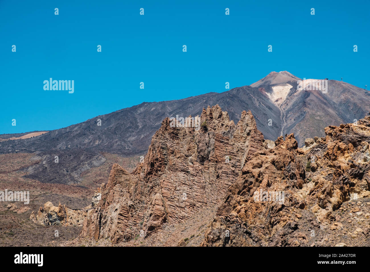 Il Teide e strati di roccia vulcanica nel paesaggio del deserto e cielo blu - Foto Stock