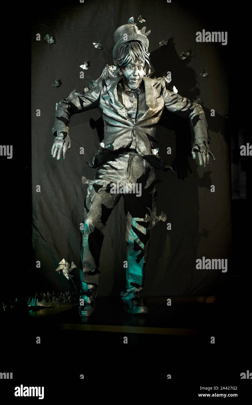 Pantomima spettacolari show eseguita dall'artista con sorpresa l'espressione del viso,vestito in tuta di colore grigio che ricorda la statua.emotivo attore mime in piedi e gesticolando su sfondo nero parete Foto Stock