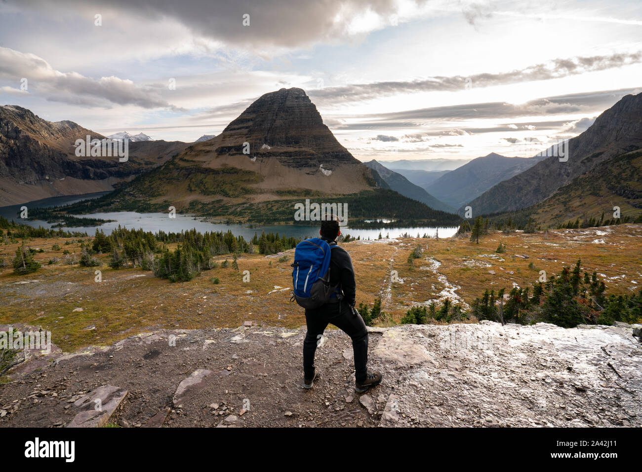 Un giovane uomo in piedi alti e guardando il paesaggio del lago nascosta sul tramonto, Montana. Foto Stock