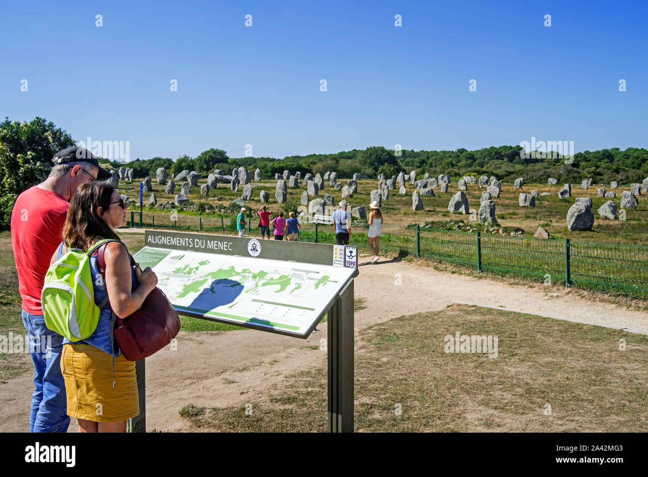 I turisti guardando le Ménec allineamenti, sito megalitico tra il Carnac pietre permanente, Morbihan, in Bretagna, Francia Foto Stock