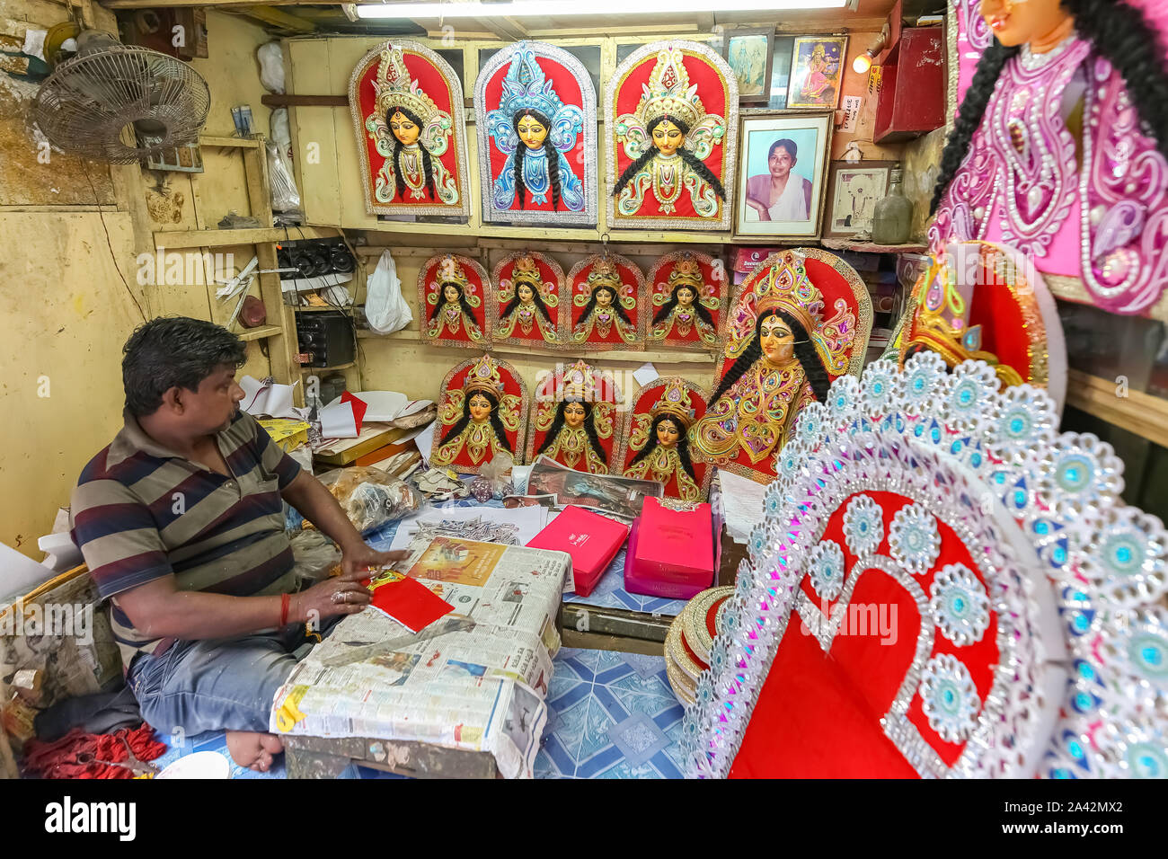 Negozio artigiano che vende busto di Dea Durga con altri oggetti festosi con vista dell'artista locale che lavora su oggetti decorativi per Durga Puja a Kolkata Foto Stock