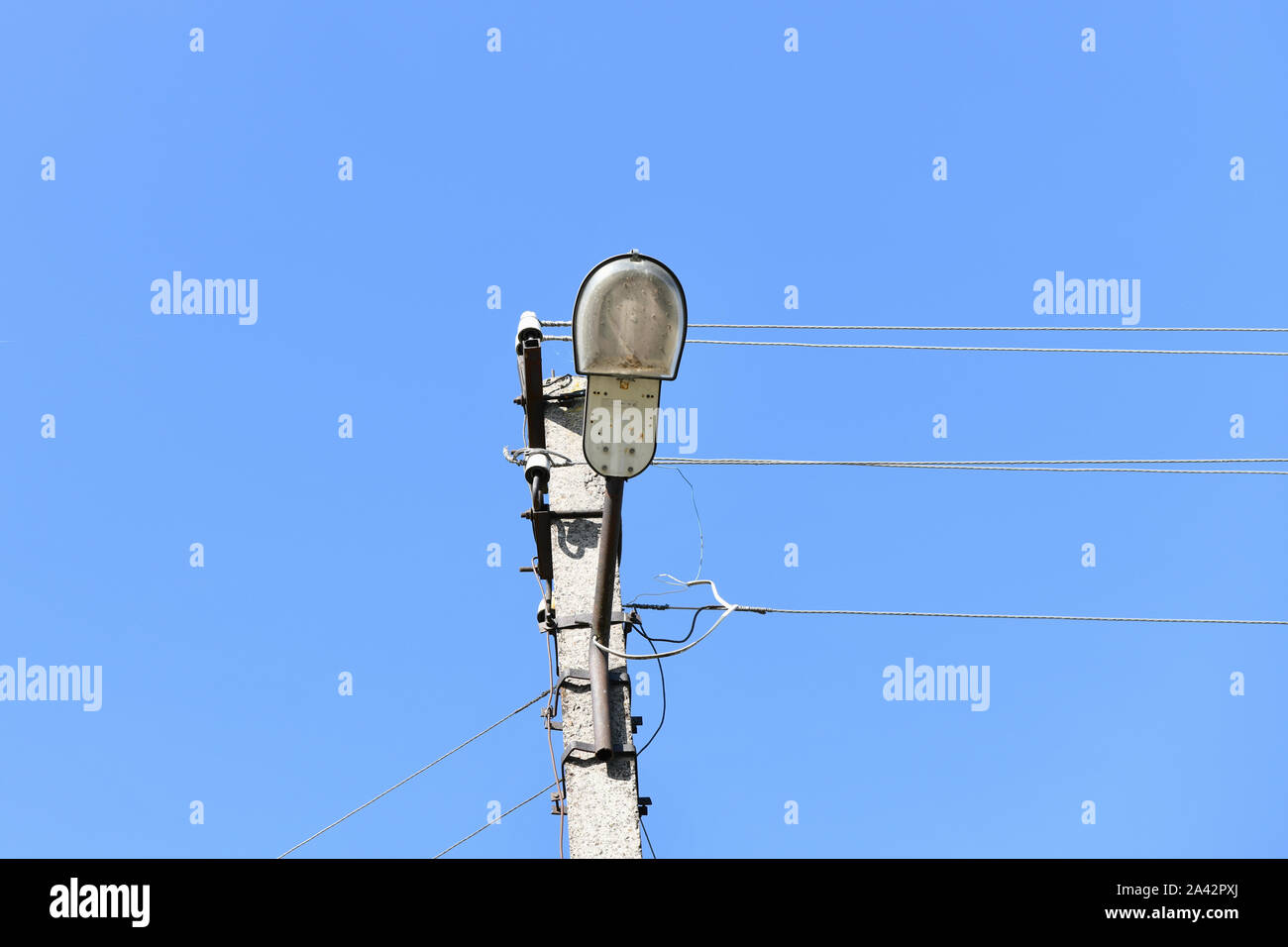 Vecchio cemento polo elettrico per la trasmissione di elettricità cablata con lampada posta su uno sfondo di un nuvoloso cielo blu. Obsoleta di me. Il THOD di alimentazione Foto Stock