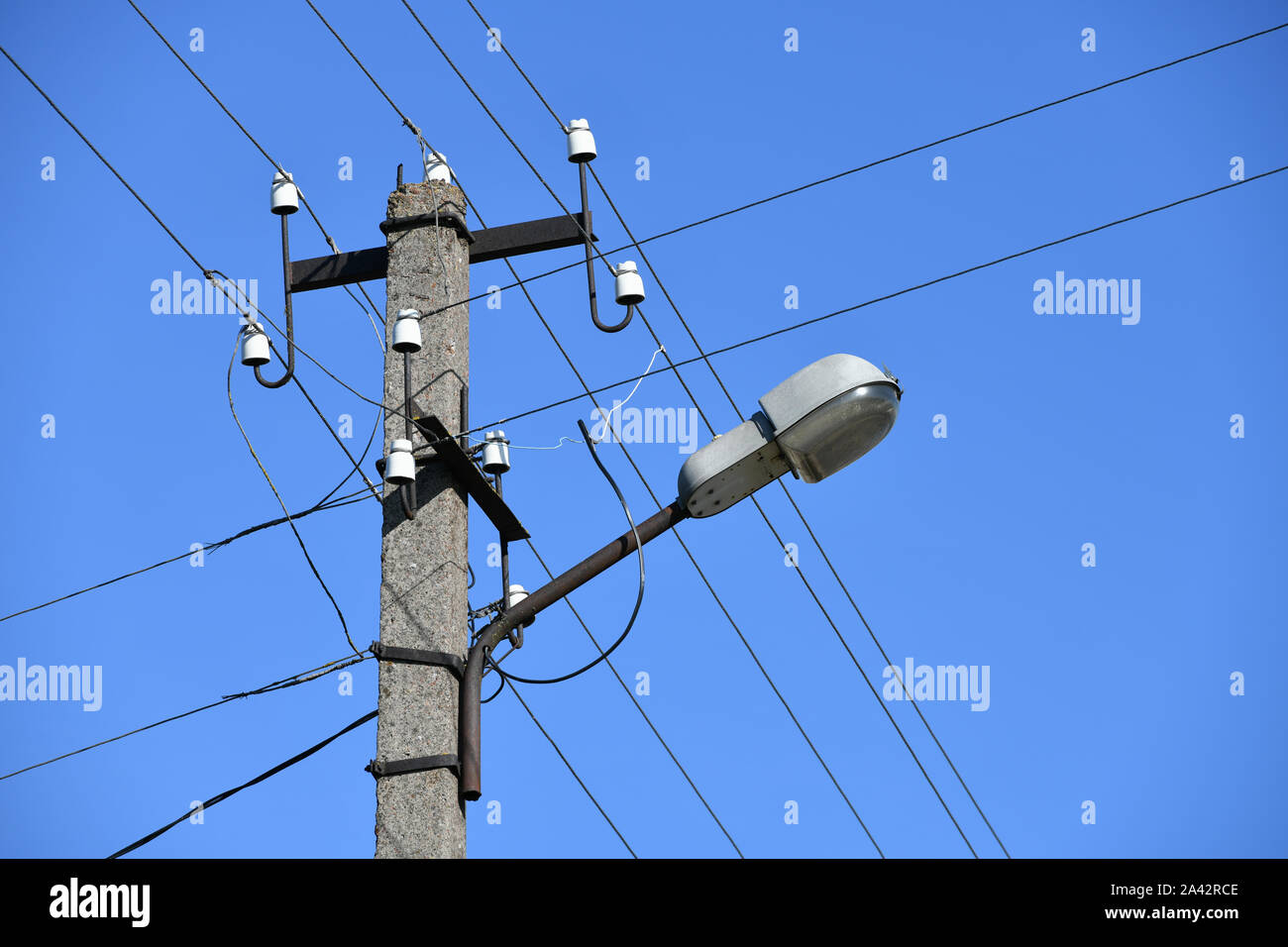 Vecchio cemento polo elettrico per la trasmissione di elettricità cablata con lampada posta su uno sfondo di un nuvoloso cielo blu. Obsoleta di me. Il THOD di alimentazione Foto Stock