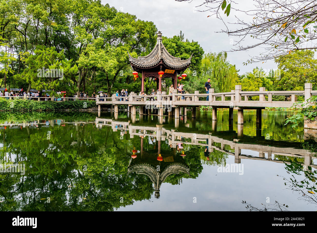 Shanghai Nanxiang Città Vecchia Canal City pittoresco Guyi Gongyuan giardino cinese con il padiglione e il ponte di pietra sul lago e la gente a piedi Foto Stock