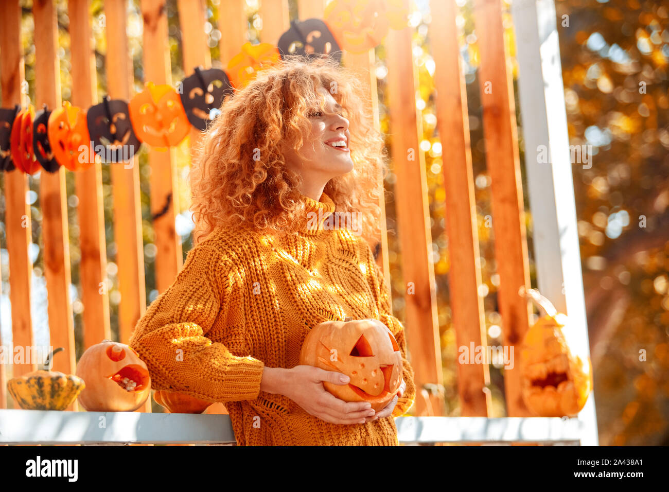 Halloween Preparaton concetto. Giovane donna in piedi all'aperto con jack-o-lantern sorridente ispirato Foto Stock