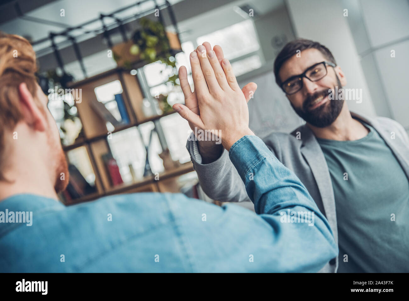 Startupers maschio lavorando insieme a Office in piedi dando alta cinque sorridente friendly Foto Stock