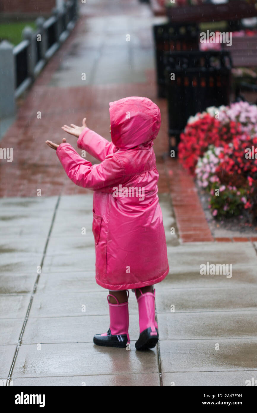 Una bambina in una giornata di pioggia in una rosa impermeabile con  abbinamento di scarponi Foto stock - Alamy
