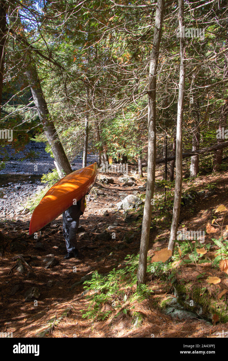 Uomo che porta un arancio in canoa lungo un aspro sentiero accanto a un fiume Foto Stock