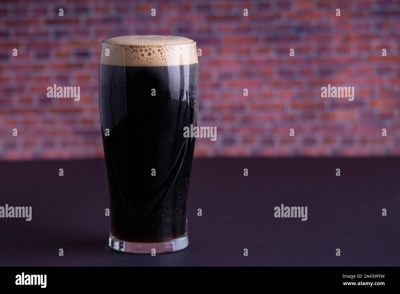 Una scura Guinness Irish Stout secca bicchiere di birra che ha origine nella fabbrica di birra a Dublino vista orizzontale Foto Stock