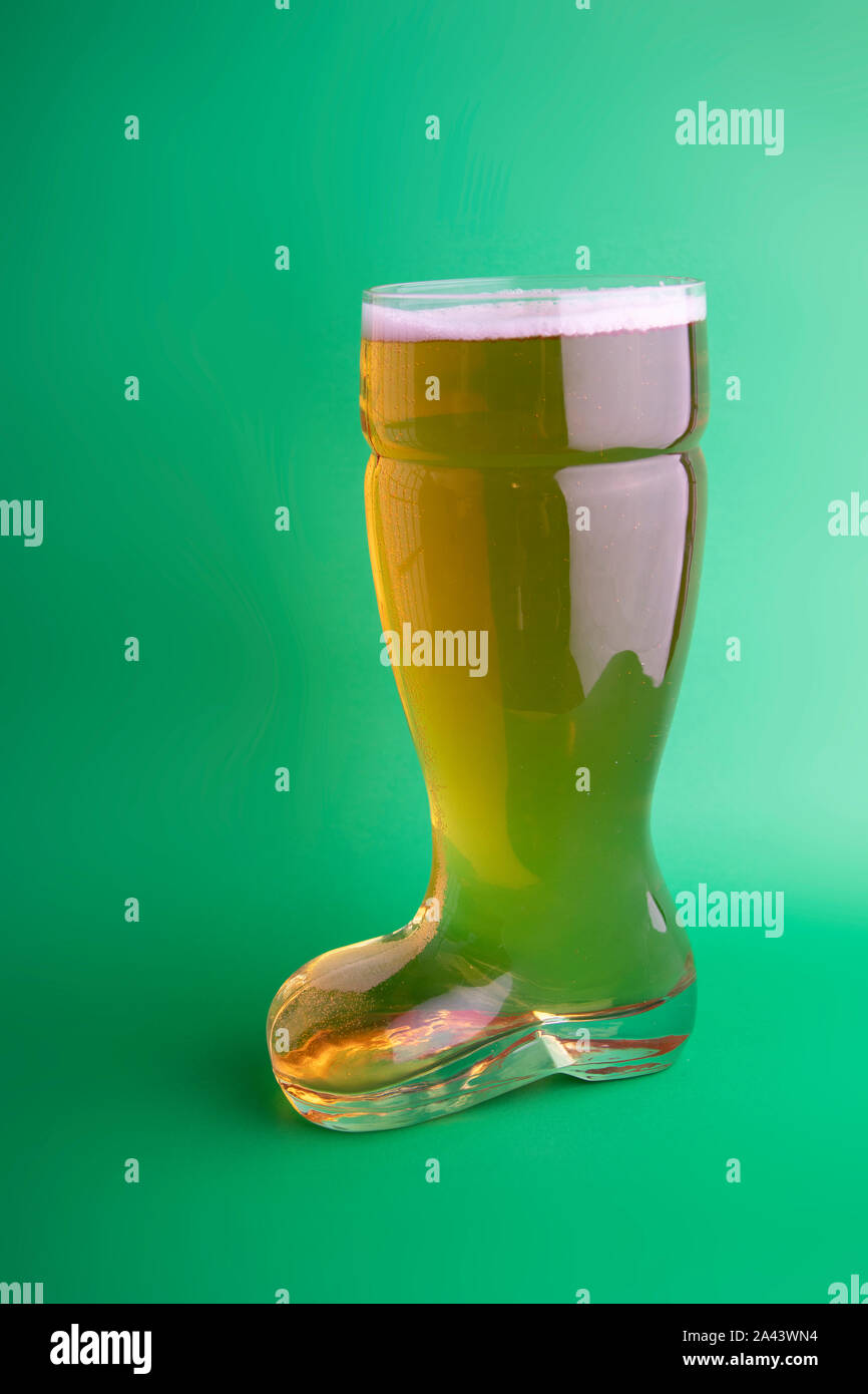 La birra nel bagagliaio di un bicchiere di birra in sfondo verde Foto Stock